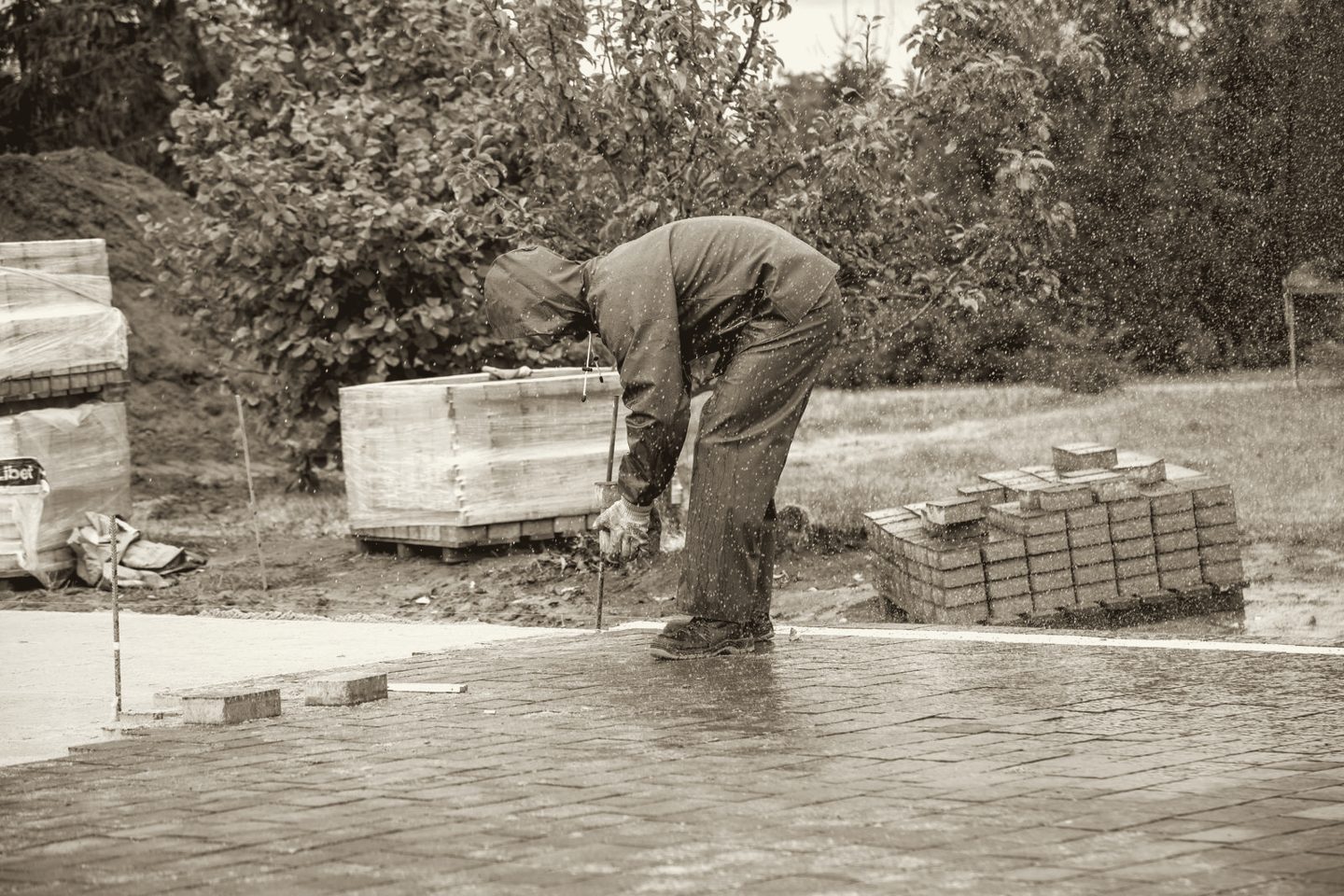 Trabajador de construcción colocando pavimento bajo la lluvia